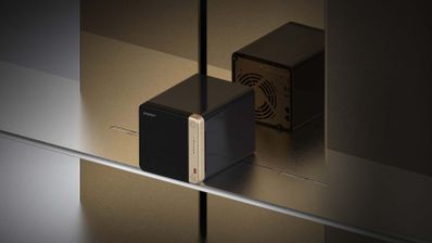 NAS compacto de sobremesa con diseño negro y frontal plateado, reflejado en superficie metálica con iluminación suave.
