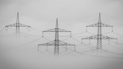 Torres de alta tensión al atardecer, simbolizando la red de distribución eléctrica y la potencia demandada por los hogares