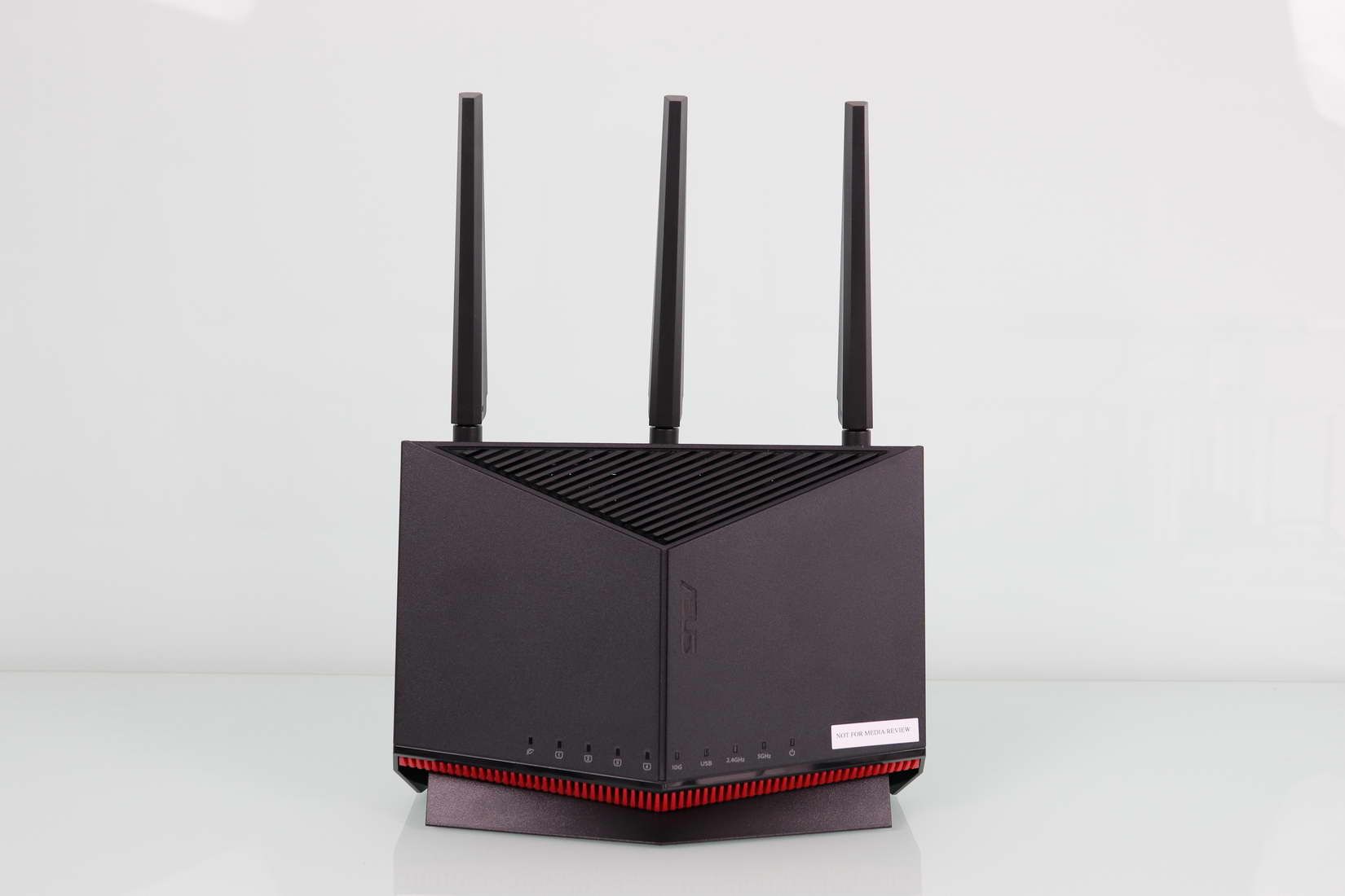 Router ASUS RT-BE86U en posición vertical con tres antenas externas y luces indicadoras de estado activas en la base.