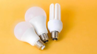 Bombilla encendida sobre un ventilador de pie, simbolizando la elección de una tarifa eléctrica eficiente para el consumo de verano.
