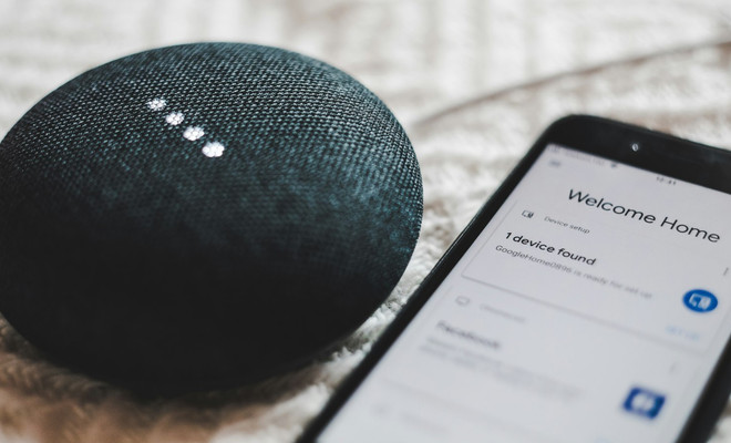 Altavoz inteligente Google Home Mini junto a un móvil con la app de configuración abierta