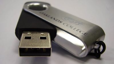 Usuario insertando un pendrive de seguridad con cifrado por hardware en un portátil para proteger documentos confidenciales