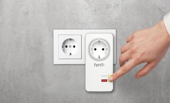 Primer plano del botón de emparejamiento de un adaptador Powerline FRITZ! siendo presionado para iniciar la sincronización segura de la red.
