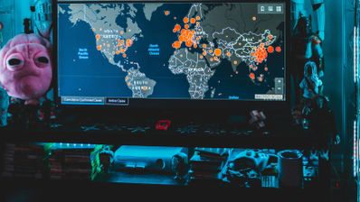 Monitor con mapa mundial iluminado que muestra puntos de seguimiento activos desde distintas regiones.