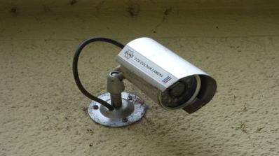 Ilustración conceptual de los riesgos de seguridad en el hogar, mostrando una cámara de vigilancia barata y vulnerable en una pared.