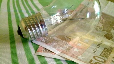 Una bombilla en una mesa junto a dos billetes de 50 euros