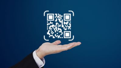 Una imagen en la que aparece una mano sosteniendo un código QR