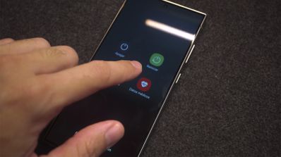 Una persona utilizando un móvil, con los botones de reiniciar y apagar en la pantalla