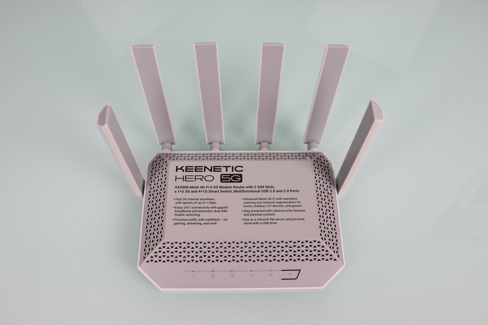 Vista superior de un router Keenetic Hero 5G de color gris con cuatro antenas externas desplegadas sobre una superficie clara.