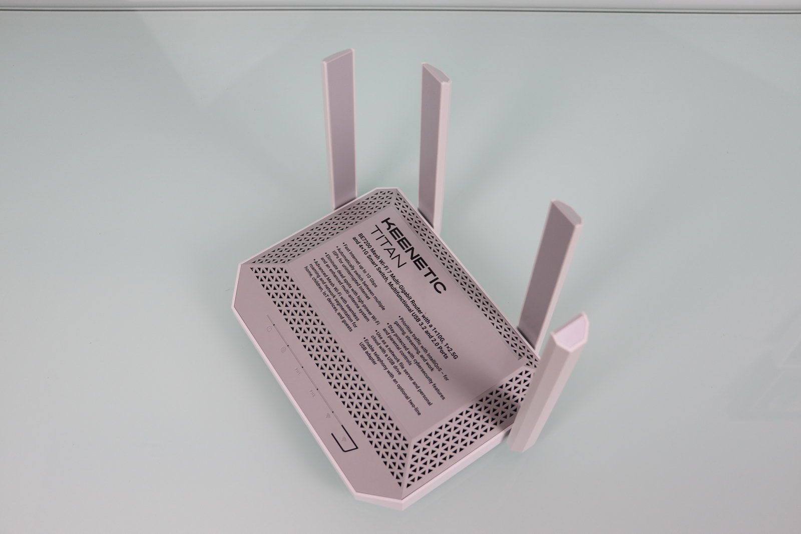 Router Keenetic Titan gris con cuatro antenas externas sobre una superficie blanca reflectante.