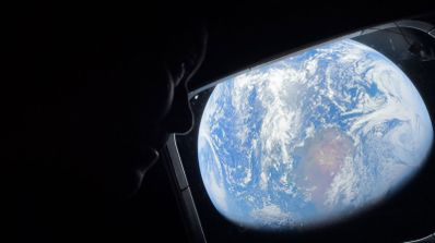 Imagen en la que aparece un astronauta en la misión de Artemis II, con la Tierra de fondo