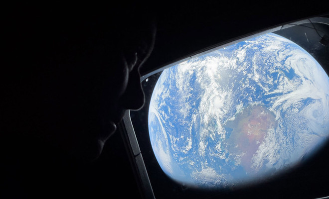 Imagen en la que aparece un astronauta en la misión de Artemis II, con la Tierra de fondo