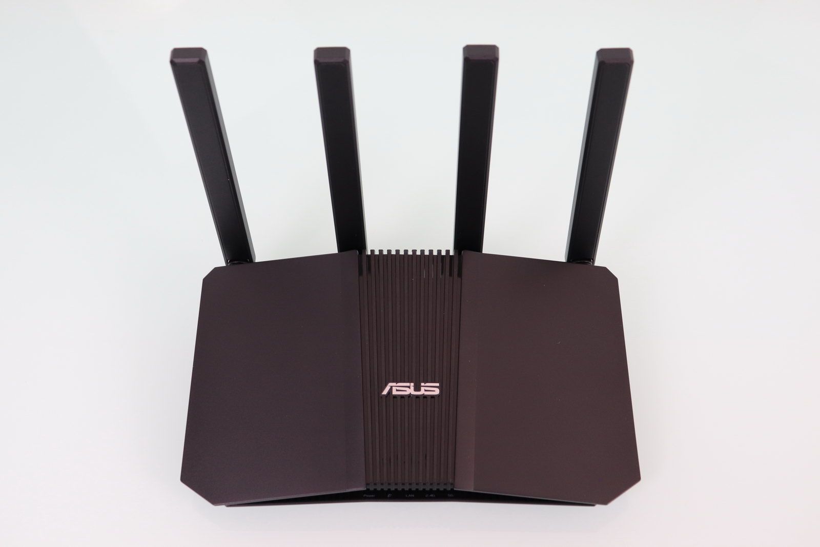 Router ASUS RT-BE59 de color negro visto desde arriba con cuatro antenas externas y rejilla central sobre fondo blanco.