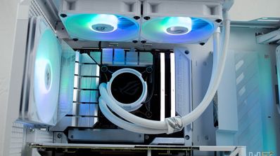 Interior de una torre de ordenador blanca con componentes iluminados por LEDs ARGB, mostrando el sistema de refrigeración líquida y los ventiladores superiores.