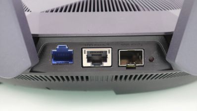 Panel posterior de un router con tres puertos Ethernet de diferentes colores y un botón de reinicio pequeño.