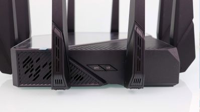 Detalle del lateral de un router ASUS ROG Rapture GT-AXE16000 mostrando los botones físicos de WPS y LED junto a varias antenas externas.