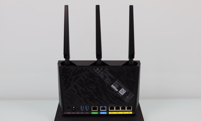 Panel posterior de un router ASUS RT-AX86U que muestra tres antenas externas, puertos Ethernet amarillos, un puerto WAN azul y conexiones USB.