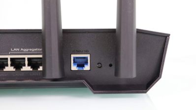 Panel trasero de un router ASUS TUF con puertos LAN y puerto WAN azul destacados junto a las antenas.