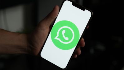 Mano sujetando un teléfono móvil con el logotipo de WhatsApp centrado en una pantalla blanca.