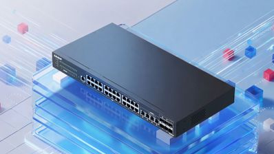 Switch gestionable QNAP QSW-M2130-4C2S24T de color negro expuesto sobre una superficie de cristal azul con efectos visuales de velocidad de datos.