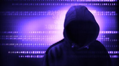 Silueta de una persona anónima con capucha frente a un fondo de código binario digital en tonos violetas.