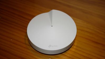 Repetidor WiFi de diseño circular blanco y minimalista sobre una superficie de madera barnizada.