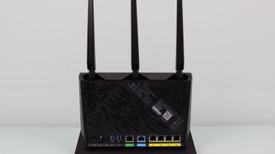 Panel posterior de un router ASUS RT-AX86U que muestra sus tres antenas externas y la disposición de los puertos de conexión.