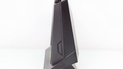 Vista de perfil de un router ASUS RT-AX86U negro con diseño angular sobre fondo blanco.