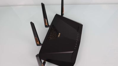 Router ASUS RT-AX88U de color negro con cuatro antenas externas y detalles en dorado sobre una superficie blanca.
