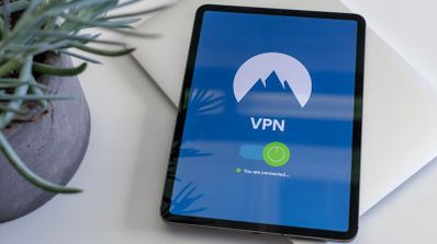 Tableta sobre una mesa blanca mostrando la interfaz de una aplicación VPN conectada con un botón verde de encendido.