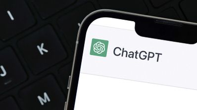 Primer plano del logotipo y nombre de ChatGPT en la pantalla de un teléfono móvil sobre un teclado de ordenador.