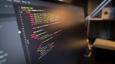 Primer plano de un monitor mostrando líneas de código de programación con sintaxis resaltada en varios colores.