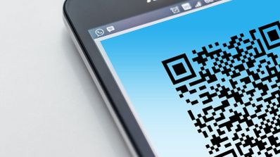 Primer plano de un código QR mostrado en la pantalla de un teléfono móvil sobre un fondo azul.