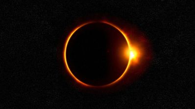 Eclipse solar total con el efecto de anillo de diamante sobre fondo estrellado.
