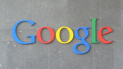 Logotipo de Google en relieve con sus colores corporativos sobre una pared de piedra gris.