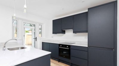 Cocina moderna con mobiliario en color gris oscuro mate y encimera blanca con isla lateral.