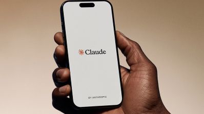 Mano sosteniendo un teléfono móvil con el logotipo de la aplicación Claude de Anthropic en pantalla.