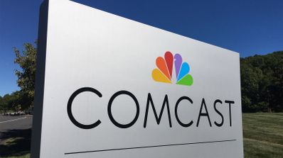 Logotipo de Comcast en un panel blanco exterior con el icono multicolor de NBC.