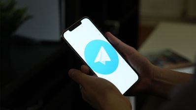 Primer plano de unas manos sosteniendo un smartphone que muestra el logotipo de la aplicación Telegram en pantalla.