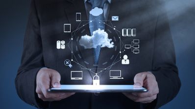 Persona con traje sosteniendo una tablet de la que emana un gráfico circular con iconos de servicios en la nube, dispositivos conectados y seguridad.