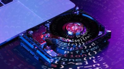 Disco duro abierto mostrando sus componentes internos sobre un fondo con líneas de código de programación en tonos azules y púrpuras.