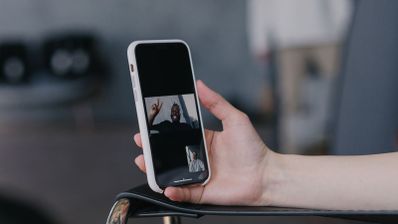 Primer plano de una mano sujetando un teléfono móvil mientras se realiza una videollamada con otra persona.