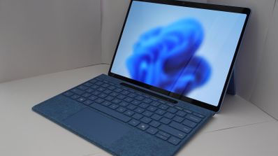 Ordenador portátil con teclado azul mostrando el fondo de escritorio predeterminado de Windows 11.
