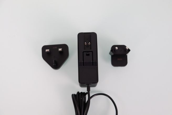 Adaptador de corriente del router ASUS GT-BN98 con cabezales intercambiables para enchufes europeos y del Reino Unido.