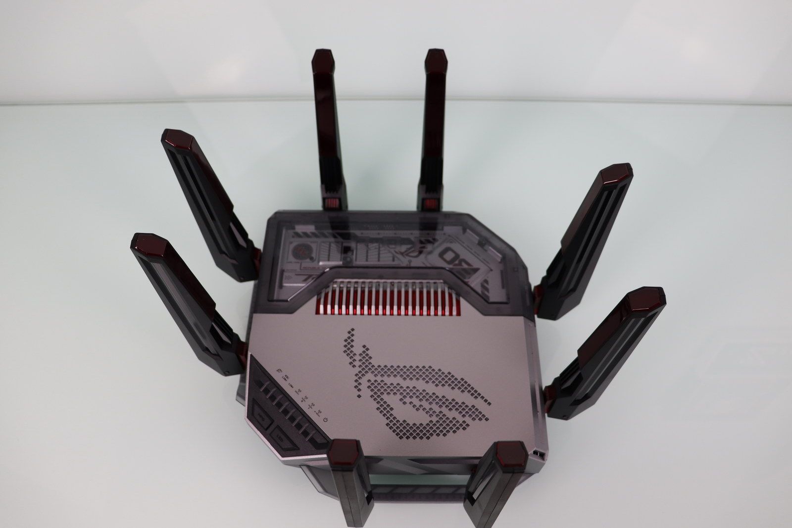Vista superior de un router ASUS ROG Rapture GT-BN98 con ocho antenas externas y logotipo iluminado sobre una superficie blanca.