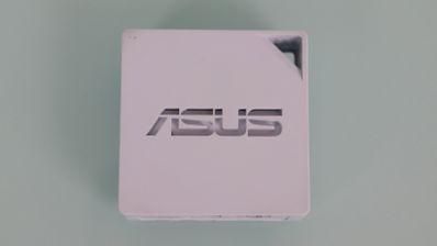 Vista superior del router portátil blanco ASUS RT-AX50 con logotipo central y orificio para transporte.