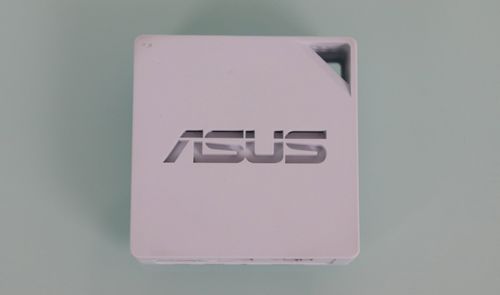 Vista superior del router portátil blanco ASUS RT-AX50 con logotipo central y orificio para transporte.