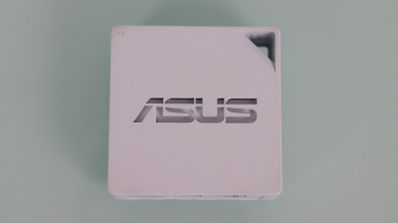 Vista superior del router portátil blanco ASUS RT-AX50 con logotipo central y orificio para transporte.