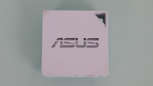 Vista superior del router portátil blanco ASUS RT-AX50 con logotipo central y orificio para transporte.