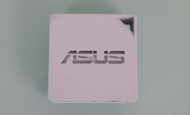 Vista superior del router portátil blanco ASUS RT-AX50 con logotipo central y orificio para transporte.